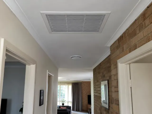 Ceiling return-air grille in a hallway with brick feature wall and doorways in Elizabeth South