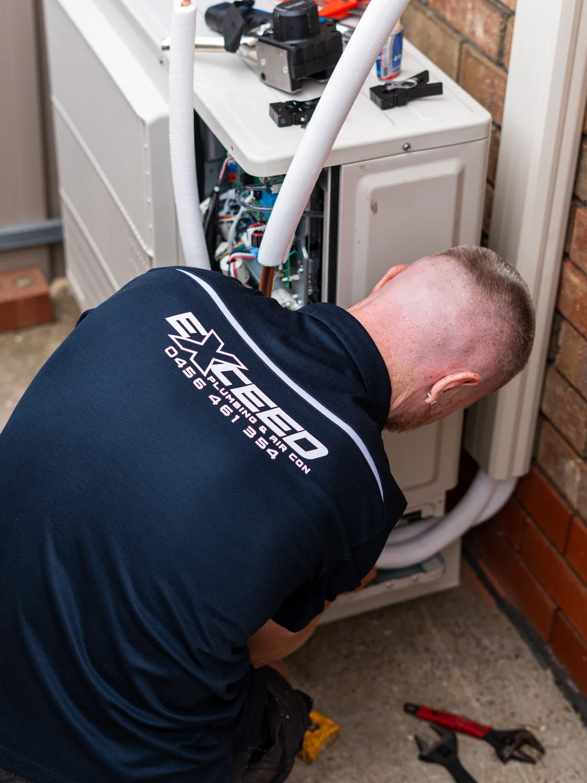 Technician servicing the inside of an outdoor air conditioning unit